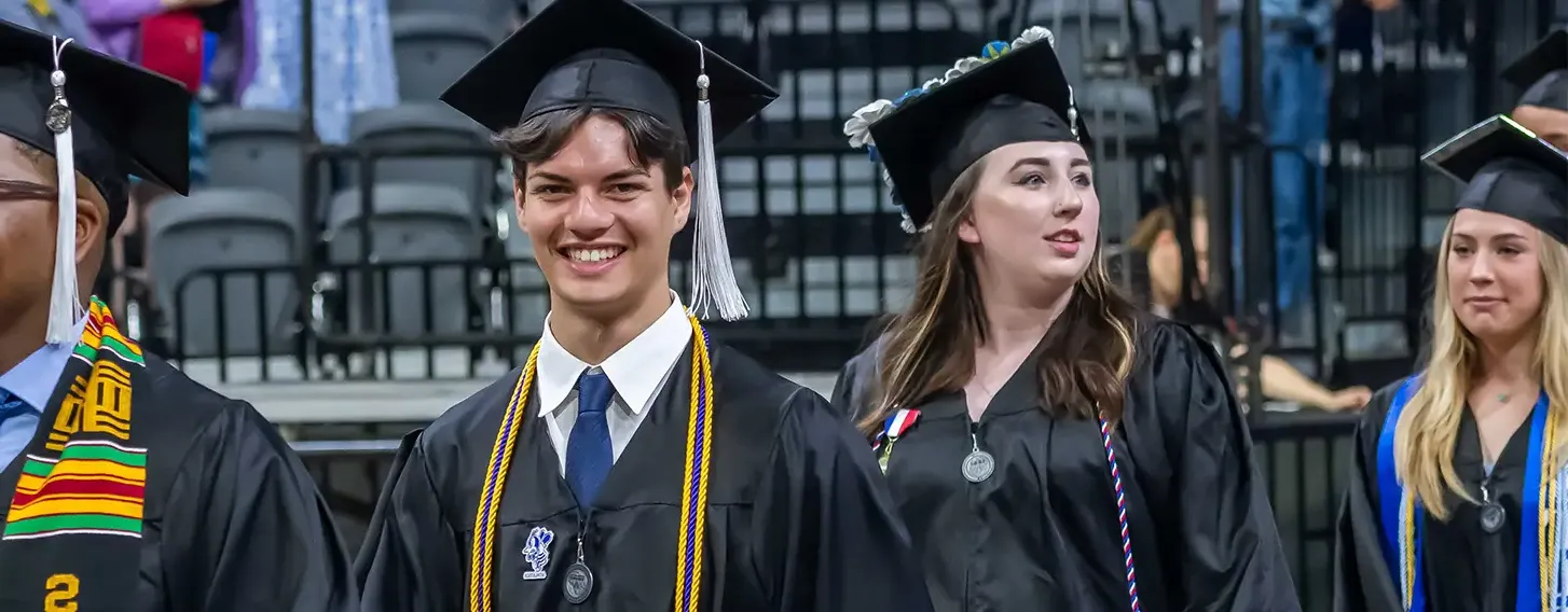 Student smiling at commencement while walking in